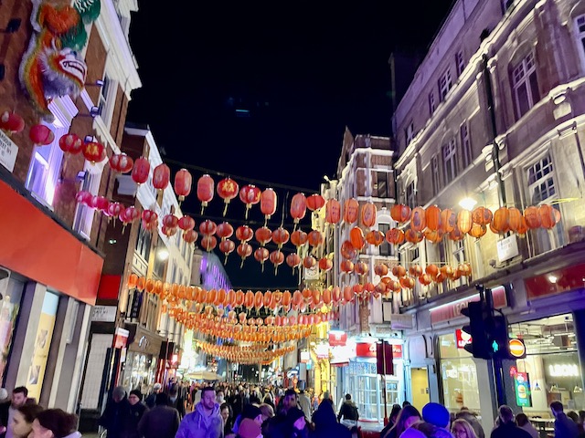 A side street, showing lots of people and red lanterns hung all the way down.