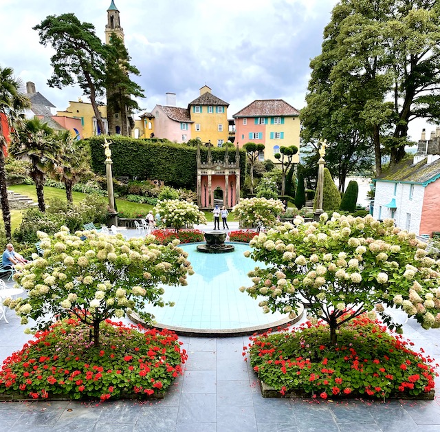 Two flower arrangements and a pool beyond, with more colourful facades beyond that
