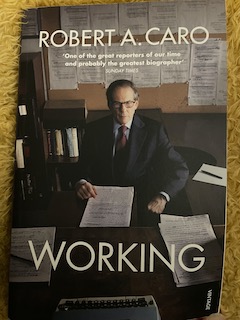 The front cover of the book has Caro sitting at his desk with the typewriter in the foreground and a board filled with pinned sheets of paper behind him.