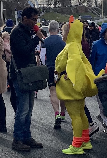 A woman dressed as a chicken being interviewed