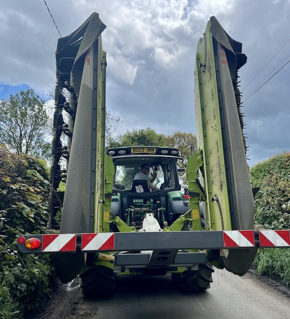 Driver of tractor waving back from his seat in the green tractor.
