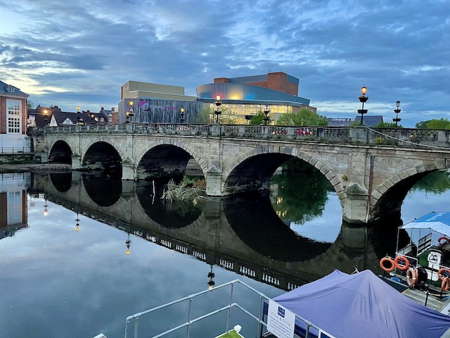 Evening river view with bridge being reflected in the water, and nice buildings beyond