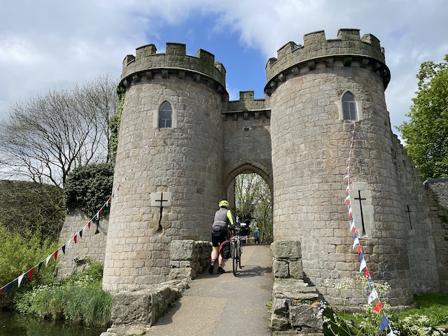 Castle turrets and an arch through which a cyclist walks