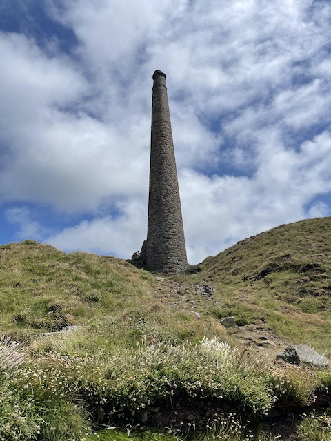 A chimney on the hills with white clouds on blue background behind