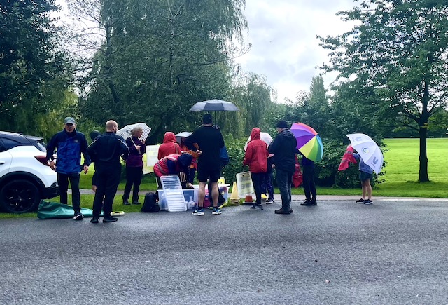 Volunteers at Parkrun standing under umbrellas in the rain.