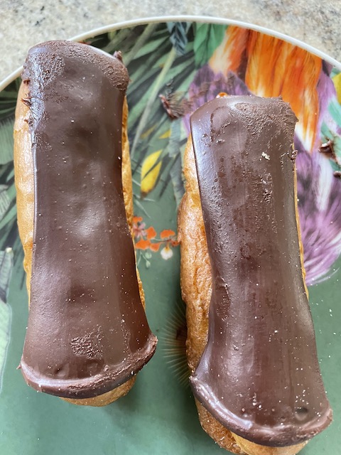 Two chocolate eclairs on a plate.