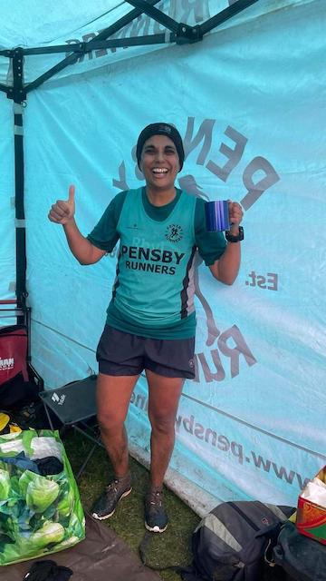 Me post-race, in the Pensby gazebo, with a mug of tea in my hand and muddy lower legs and feet. 