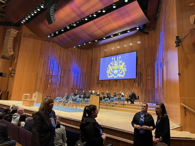 Main stage of the auditorium at the Barbican Centre. Brass band at the back. Some ushers standing in the foreground.