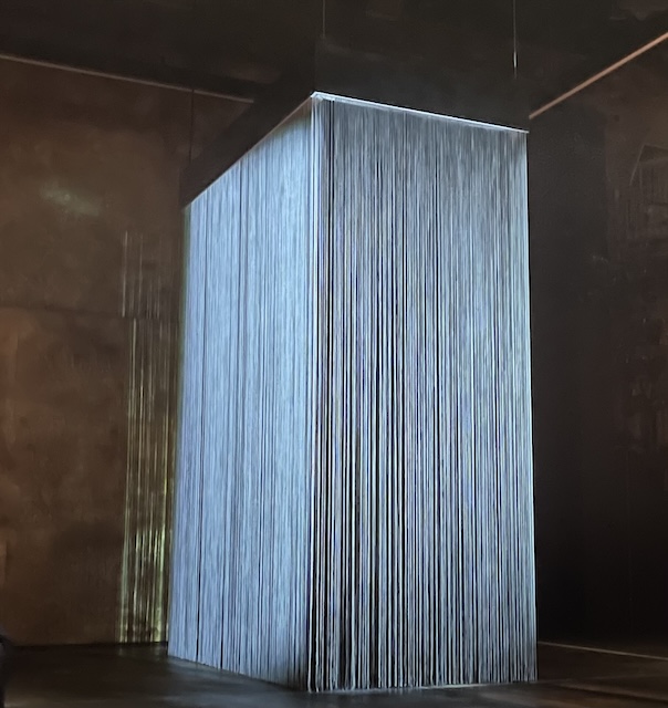 A rectangular curtain of light strands on the stage as the sole stage prop to begin with.