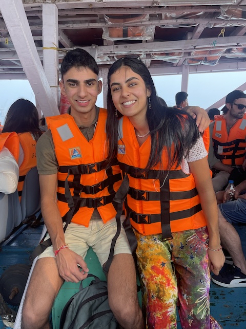 My niece and nephew sitting on the ferry boat with bright orange life jackets. Other people are sitting behind them.
