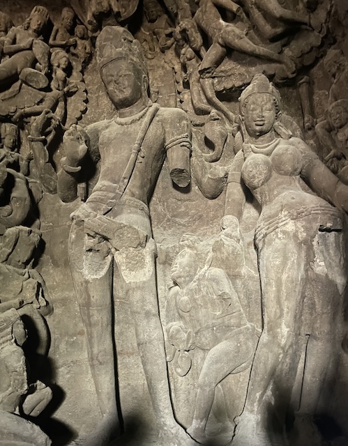 A carved statue of Shiva and Parvati. Shiva has one arm missing.