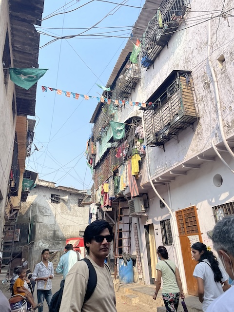 A narrow street in Dharavi with flags and wires strung from home to home in the air