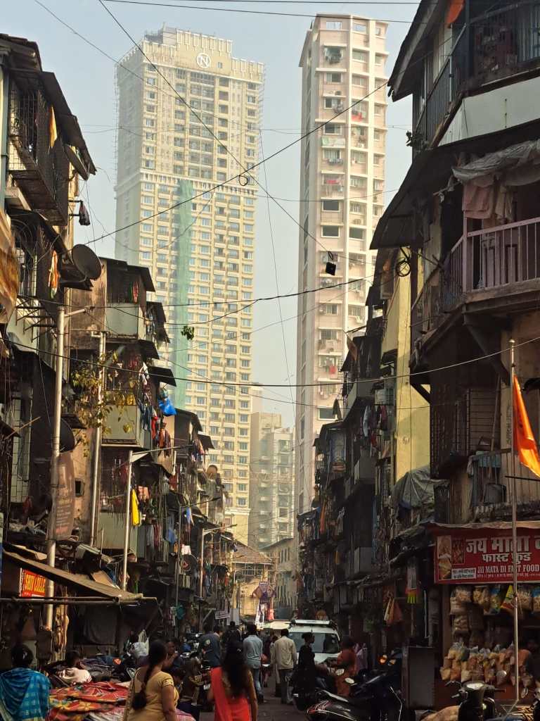 A view of a very poor street with two skyscrapers in the background