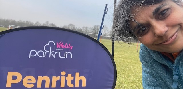 Me in front of the Penrith Parkrun sign, with the grass in the background.