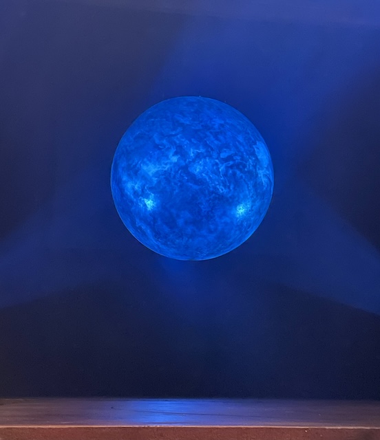 A prop of the moon on the stage in a predominantly blue light