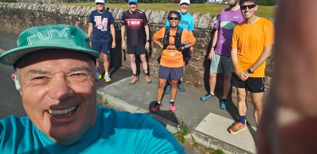 A runner, taking a selfie with several runners behind him