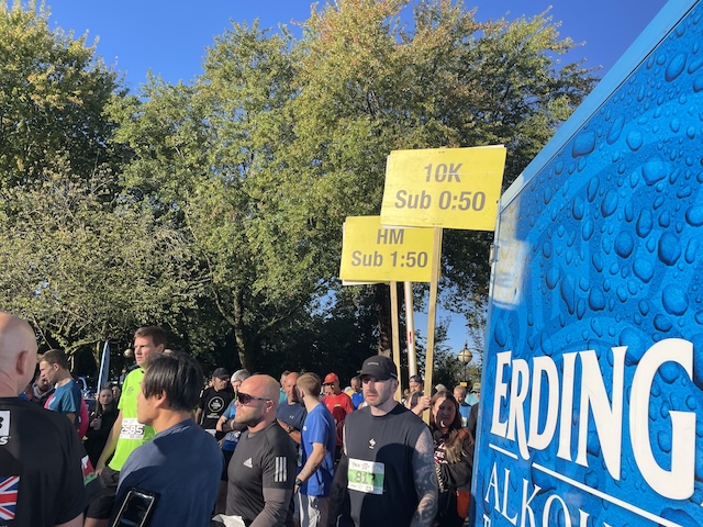 Runners walking past and banners saying HM Sub 1:50 and 10K Sub 0:50 go past with them.
