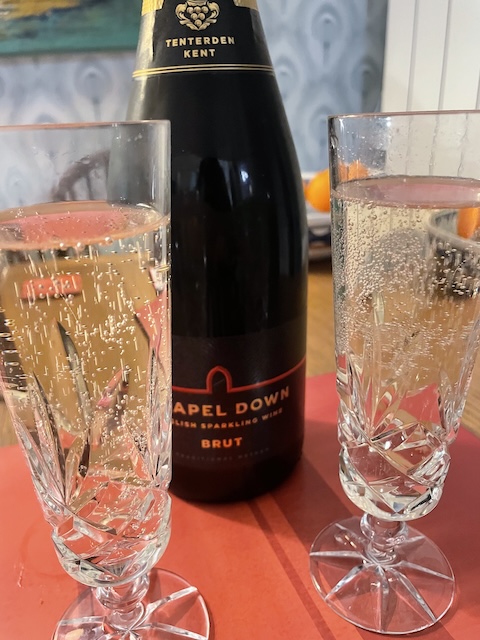 Two flutes filled with sparkling wine and a bottle of Chapel Down Brut behind them