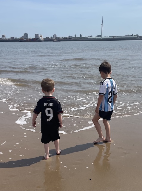 Two barefoot boys on the beach at the water's edge