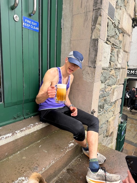 Pete drinking a large beer on the steps of Keswick Moot Halll