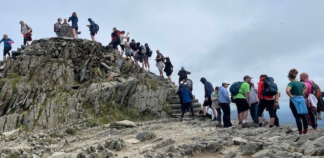 A queue of people waiting to take their photos at the top of Snowdon.