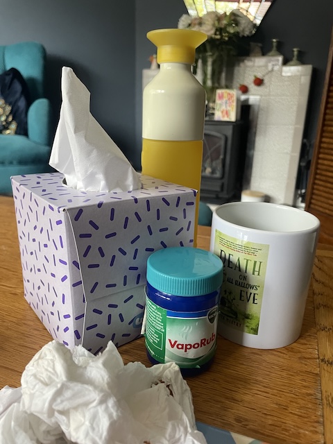 An array of tissues, Vicks, a mug and a bottle of water on the table